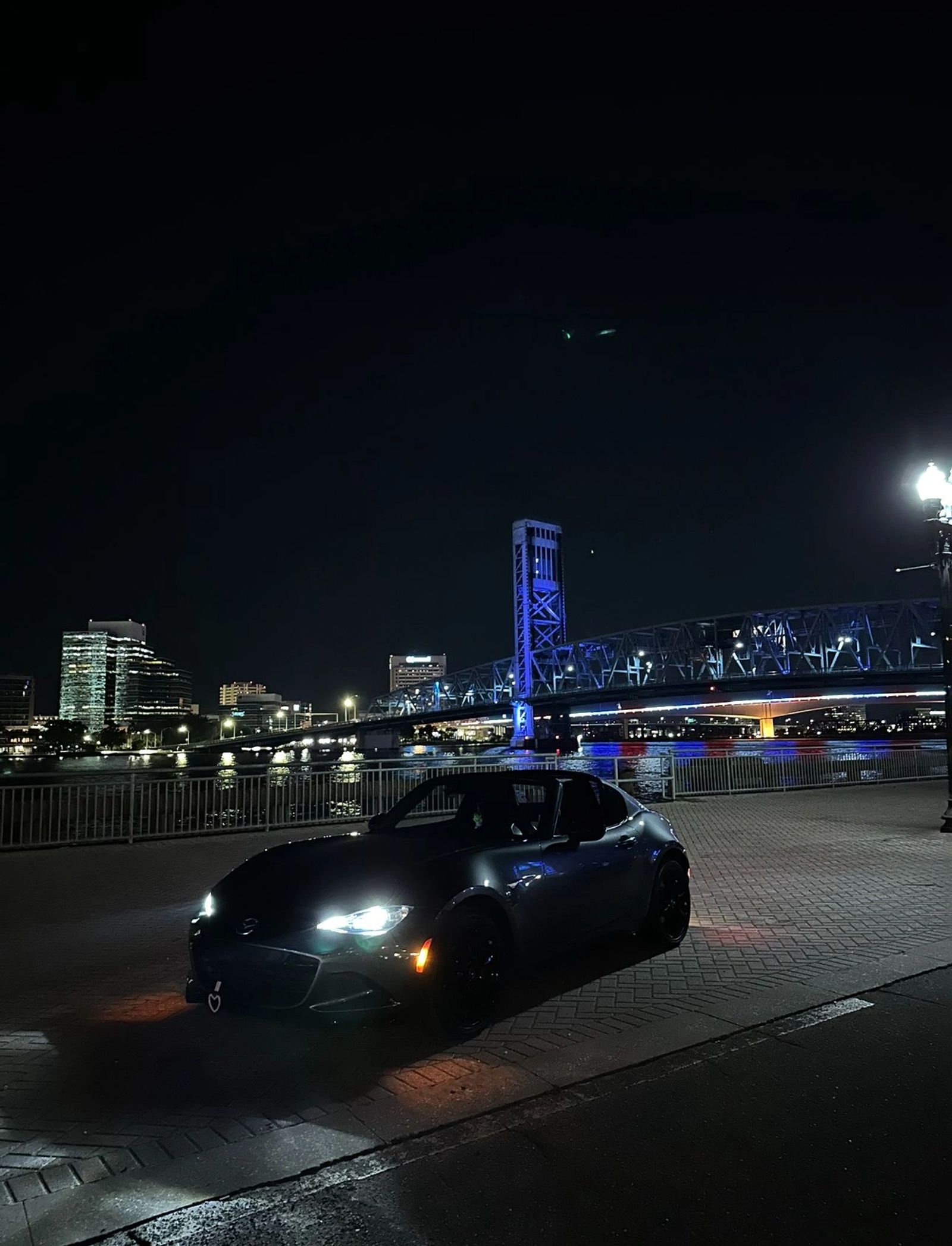 Miata with illuminated headlights on a Miami night