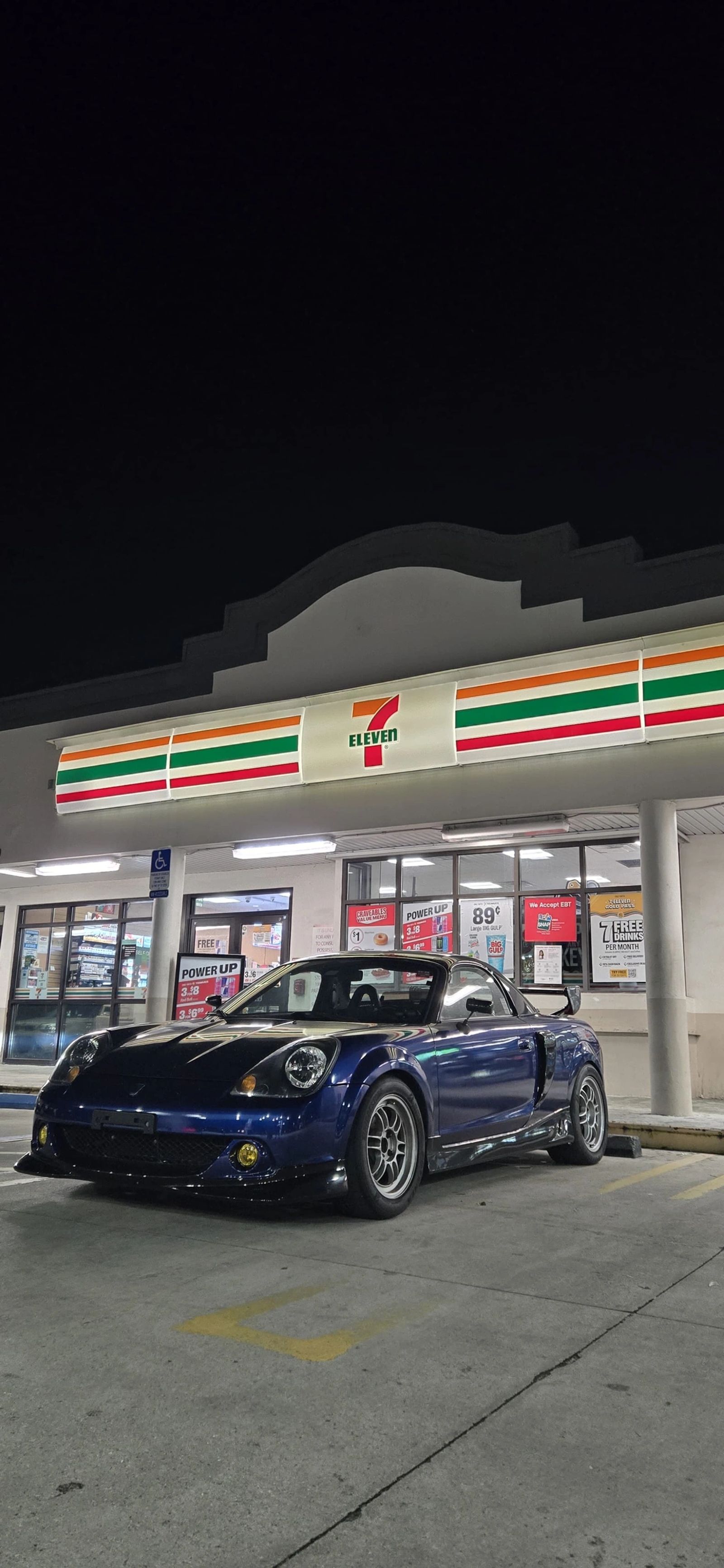 Miatas gathered outside a brightly lit convenience store at night
