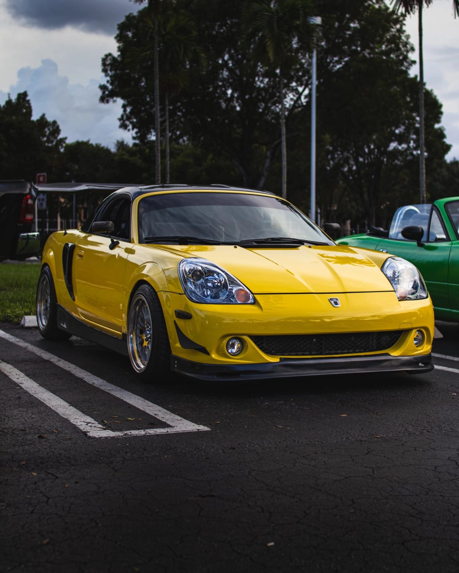 Yellow Miata parked under the trees