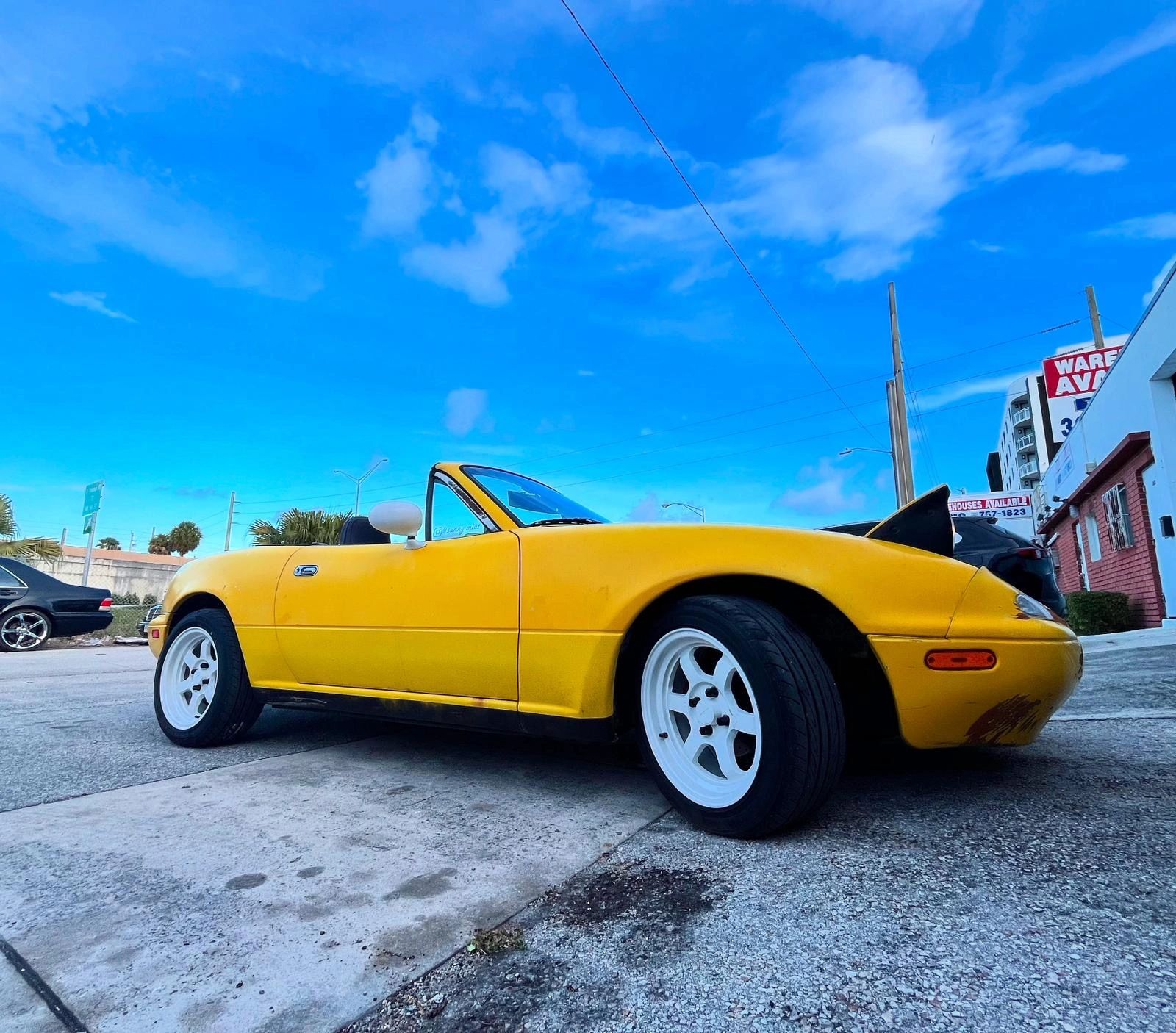 Yellow classic Miata under Miami’s bright blue sky
